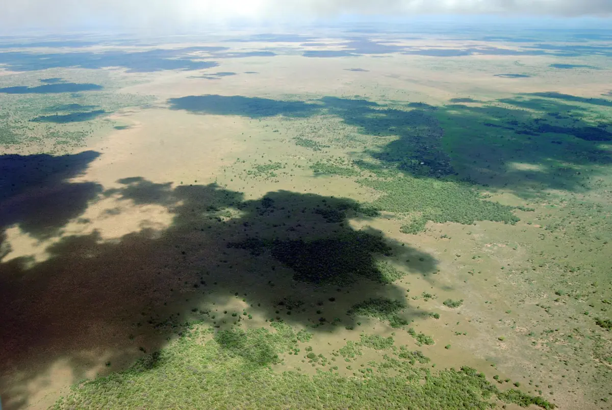 Aerial view of green plains and lakes with cloud shadows