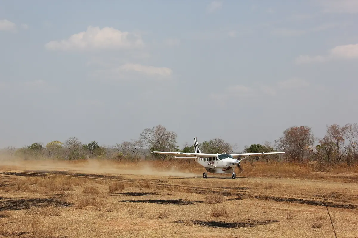 Small plane landing on a dusty airstrip in dry bush