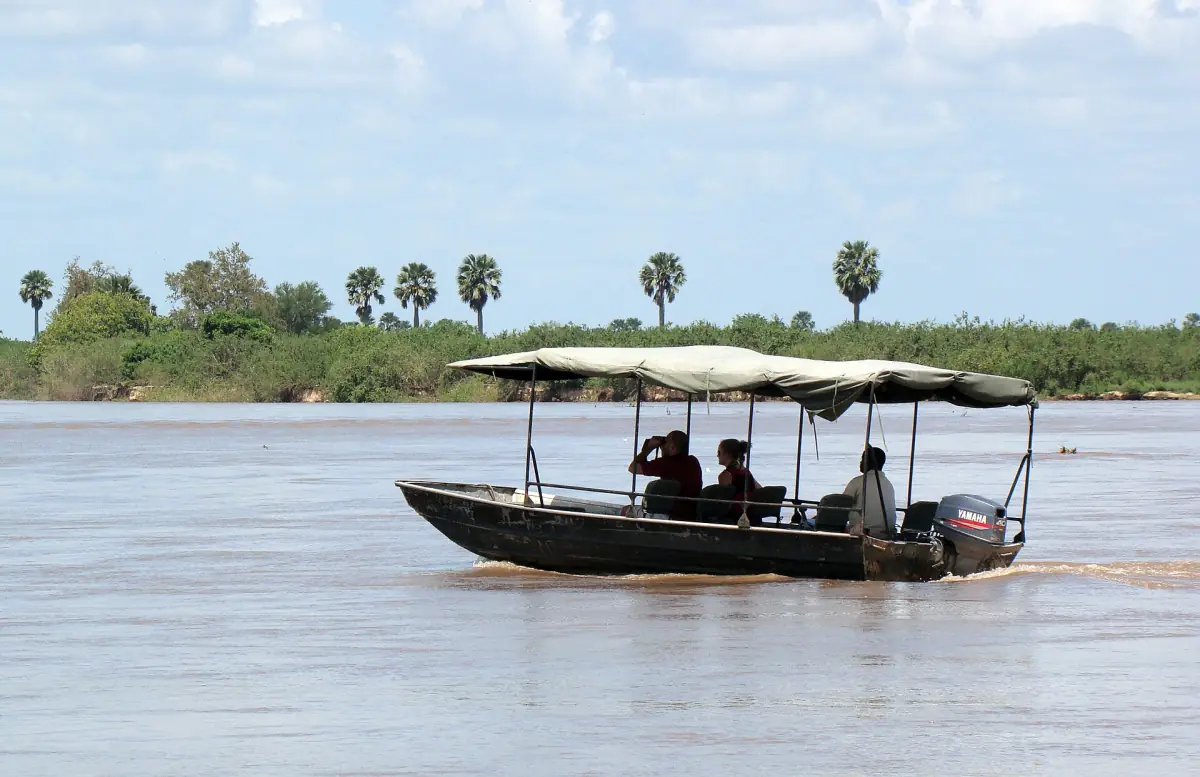 Kleines Boot mit Dach und Gästen auf dem Rufiji vor Palmen